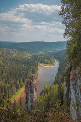 High single rock in the form of a column, against the background of the river, island and dense forest