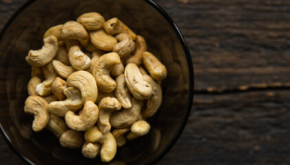 Cashew nuts in a small plate on a vintage wooden table as a background. Cashew nut is a healthy vegetarian protein nutritious food.