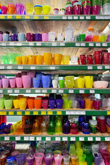 Variety of flower pots are sold at the store. Rows of different colorful pots for indoor plants on shelves in a supermarket. Vertical view.