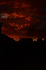 Fototapeta premium The sun is setting in a burnt orange sky as the city transforms into beautiful black silhouettes