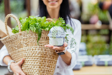 Close up of unrecognizable woman holding wicker bag full of vegetables, greens, baguette at the...
