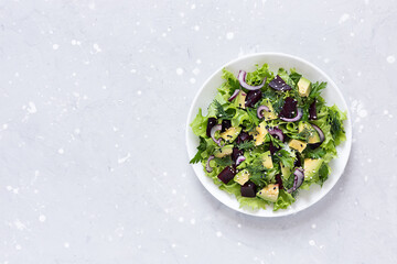 Healthy vegetarian salad of avocado, beetroot and greens in a white bowl. Top view, copy space