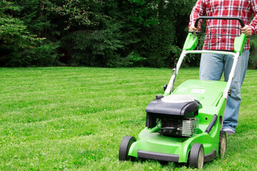 A man mowing the lawn. Cutting grass. Man working on a backyard. Man cutting grass in the garden with lawn mower