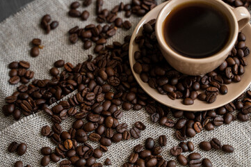 Coffee cup with roasted coffee beans on linen background. Mug of black coffe with scattered coffee beans. Fresh coffee beans.