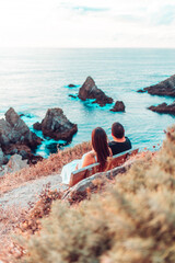Couple contemplating the ocean from a bench