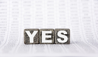 three stone cubes on the background of white financial statements, tables with the word yes. Strong business concept