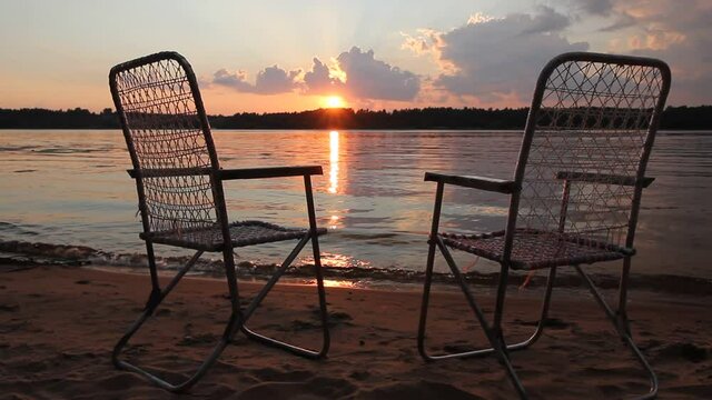 Wicker chairs on the river bank at sunset