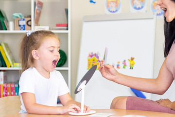 developmental and speech therapy classes with a child-girl. Speech therapy exercises and games with a mirror and cards