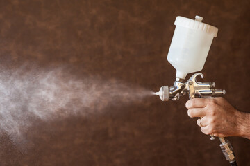 Close up of a spray paint gun with brown background