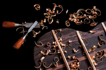 Back of guitar under construction with chisels and wood chips