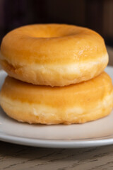 Two fresh donuts for breakfast on a wooden table