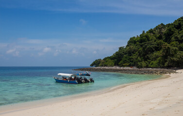 Fototapeta na wymiar Tourist boats moored on a beach on the tropical island of Pulau Tulai, Malaysia