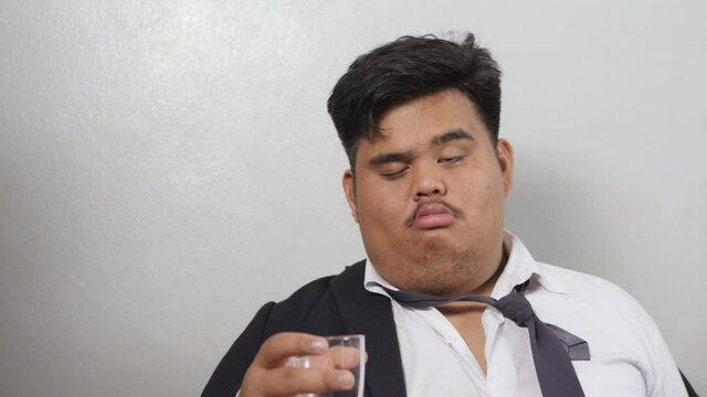 A funny Asian fat businessman wearing a suit was drunk heavily and delirious,  asked for more liquor and someone poured alcohol Looks funny.