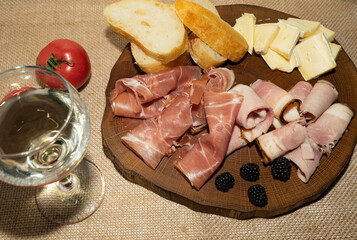 Wine appetizer. Ham, Parma ham, baguette, Cheese on a wooden stand.