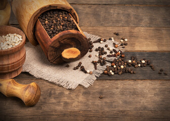 clove spices, pepper, anise, cardamom in wooden boxes on burlap on an oak table