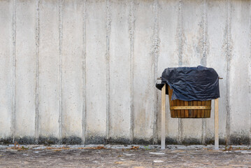wooden trash bin on gray concrete wall background