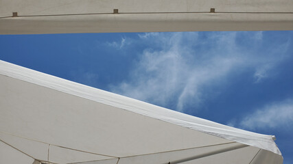 Blue sky and white clouds. Textile textures of white beach umbrellas with high sky on backdrop