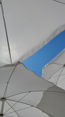 White umbrella on the beach. Closeup inside white beach sunshades