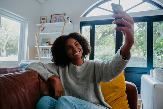 mixed-race woman taking selfie on the couch.