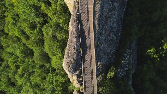 Revealing Aerial fly up view of wooden road on top of mountain steep cliff, transportation concept 