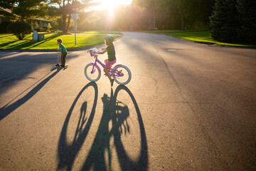 Young girl riding her bike in neighborhood at sunset