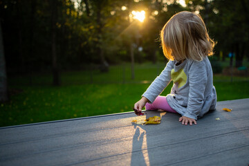 Young girl looking at fall leaves in backyard