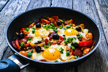 Shakshuka - fried eggs with sausages and vegetables in frying pan