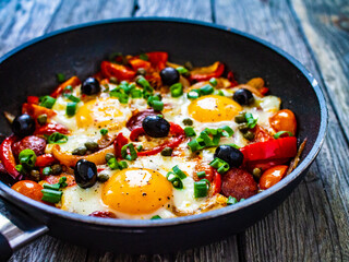 Shakshuka - fried eggs with sausages and vegetables in frying pan