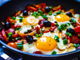 Shakshuka - fried eggs with sausages and vegetables in frying pan