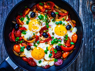 Shakshuka - fried eggs with sausages and vegetables in frying pan