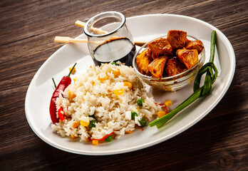 Chicken nuggets, white white rice, soy sauce  and vegetables served on wooden table