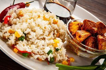 Chicken nuggets, white white rice, soy sauce  and vegetables served on wooden table