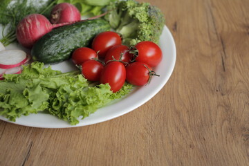 Fresh vegetables in a white plate on a wooden table