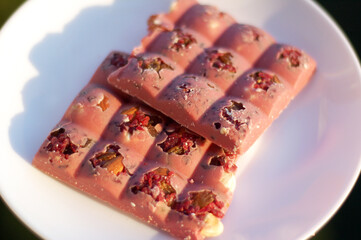 Food. Sweets. Pink chocolate with nuts on a white plate.