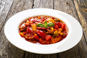 Delicious stew - vegetable with sausages on wooden table