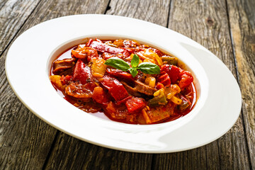 Delicious stew - vegetable with sausages on wooden table
