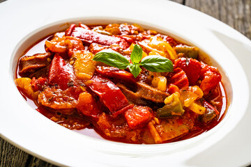 Delicious stew - vegetable with sausages on wooden table