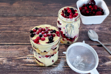 trifle with mixed berries in mason jars 