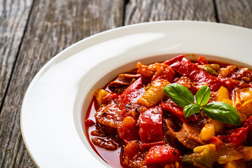 Delicious stew - vegetable with sausages on wooden table