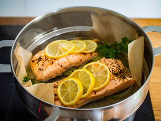 Steamed salmon steaks with lemon and parsley in pot

