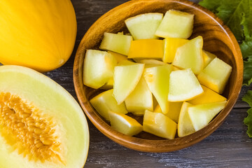 pieces of ripe yellow melon in a wooden bowl close-up. background with melon.