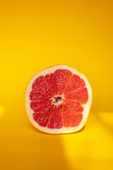 Half of grapefruit on orange background with sun stripes