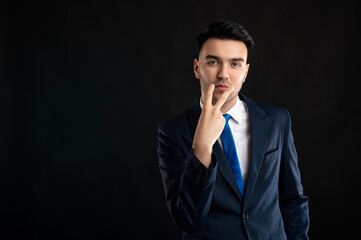 Portrait of business man wearing blue business suit and tie doing watch me gesture