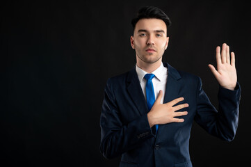 Portrait of business man wearing blue business suit and tie taking oath gesture