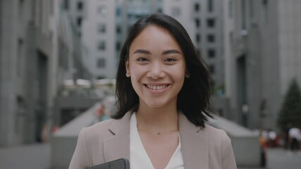 Smiling asian young woman in formal outfit looking to camera outside on street feel happy businesswoman portrait business beautiful modern manager pretty slow motion - Powered by Adobe