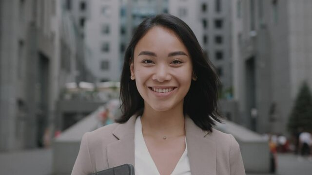 Smiling asian young woman in formal outfit looking to camera outside on street feel happy businesswoman portrait business beautiful modern manager pretty slow motion