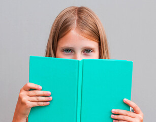 Close up portrait of close cover face behind diary. Girl ready to continue reading isolated on grey background