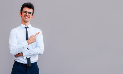 Young handsome businessman with beaming smile pointing with finger