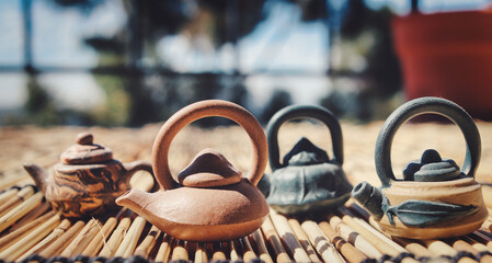 Miniature teapots on a bamboo mat in the sun