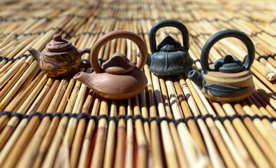 Miniature teapots on a bamboo mat in the sun